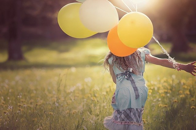 Bambina con palloncini in un campo